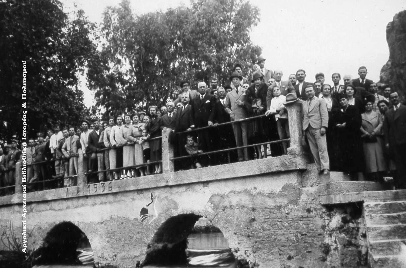 Ο Δήμαρχος Άργους Κωνσταντίνος Μπόμπος (με το μαύρο κουστούμι και το μαντίλι στο πέτο) στο γεφυράκι του Κεφαλαρίου, πιθανόν μετά από κάποια εκδήλωση, περίπου το 1937.